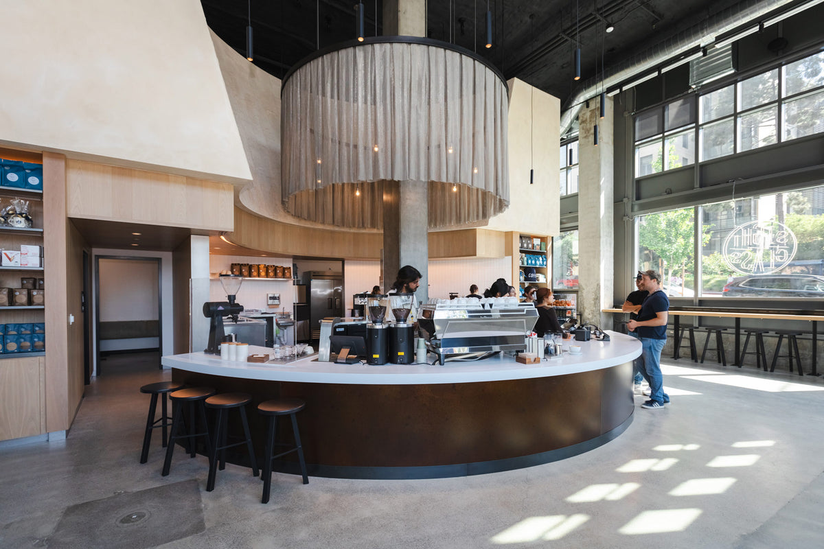 Modern coffee shop interior with a curved counter and bar stools.